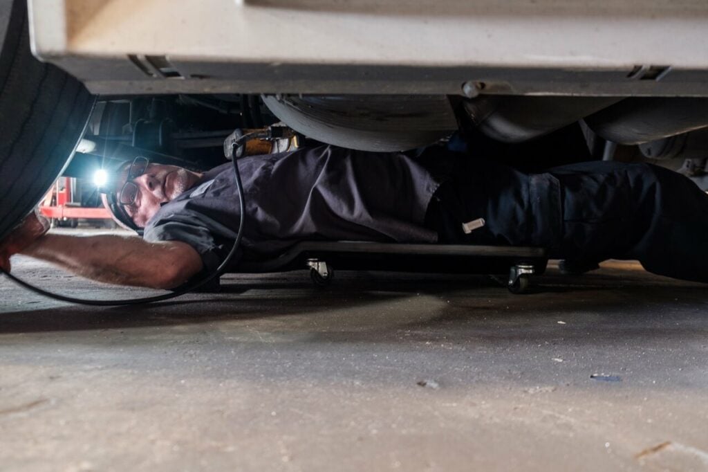 HET Certified mechanic performing brake inspection and service on a semi truck.