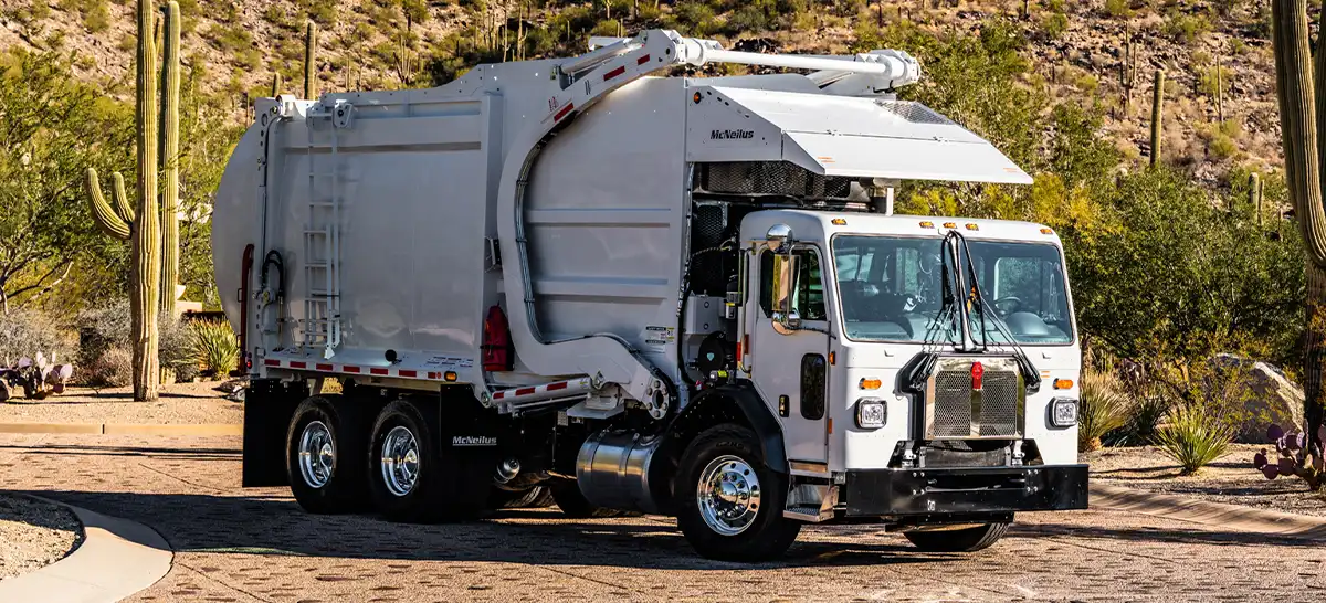 A Kenworth L770 refuse truck parked on a road in a desert.